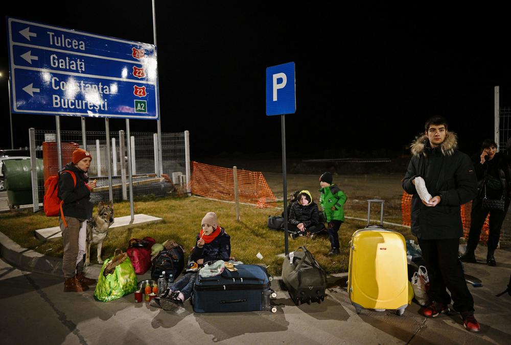 Ukrainians rest after finally reaching Romania at the Isaccea-Orlivka border crossing. They are among tens of thousands leaving Ukraine.