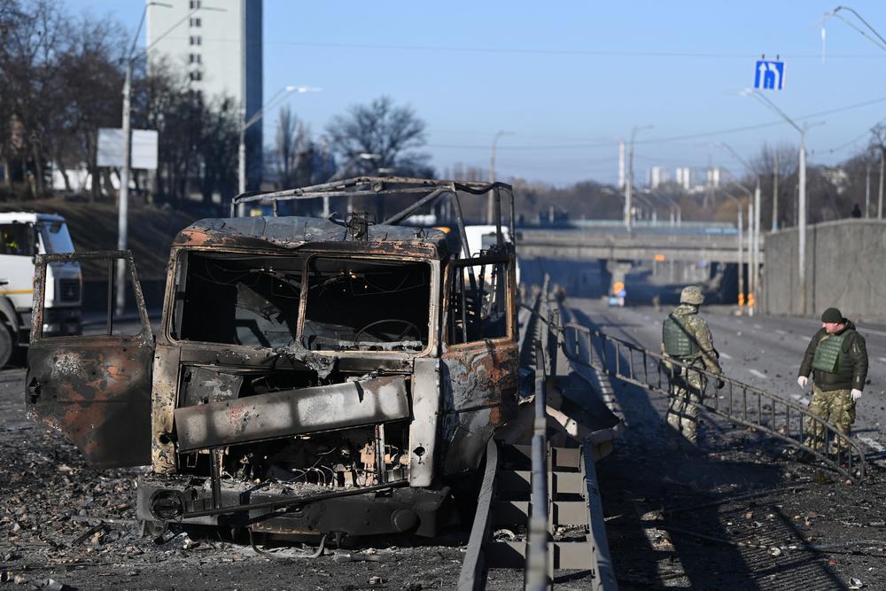 Ukrainian soldiers stand near a damaged Ukrainian army vehicle on the west side of Kyiv on Saturday.