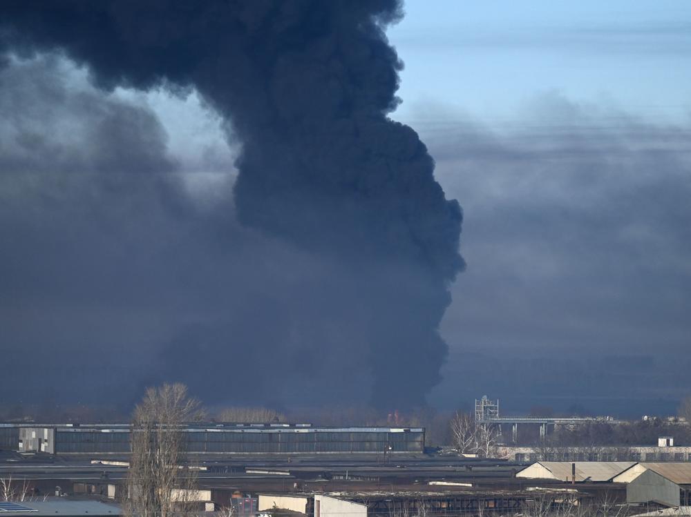 Black smoke rises from a military airport in Chuhuiv, near Kharkiv, Ukraine, on Thursday. Humanitarian organizations say Russian forces are using cluster munitions in their bombing and shelling of Ukraine.