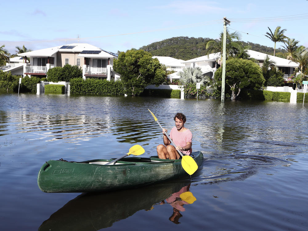 A man paddles a canoe through flood water in Cabarita, Australia, on Tuesday.