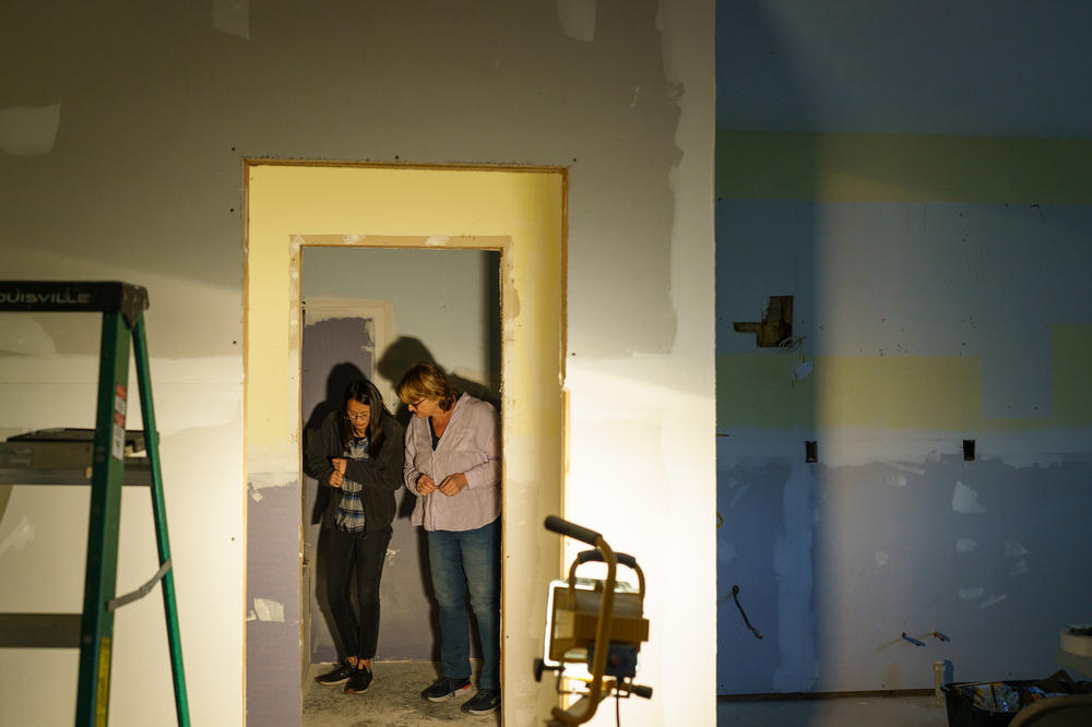 Gretchen Turner and her daughter, Zoe, survey the progress being made on their garage, which is being converted into a small family quarters. Work on their home is still several months away.