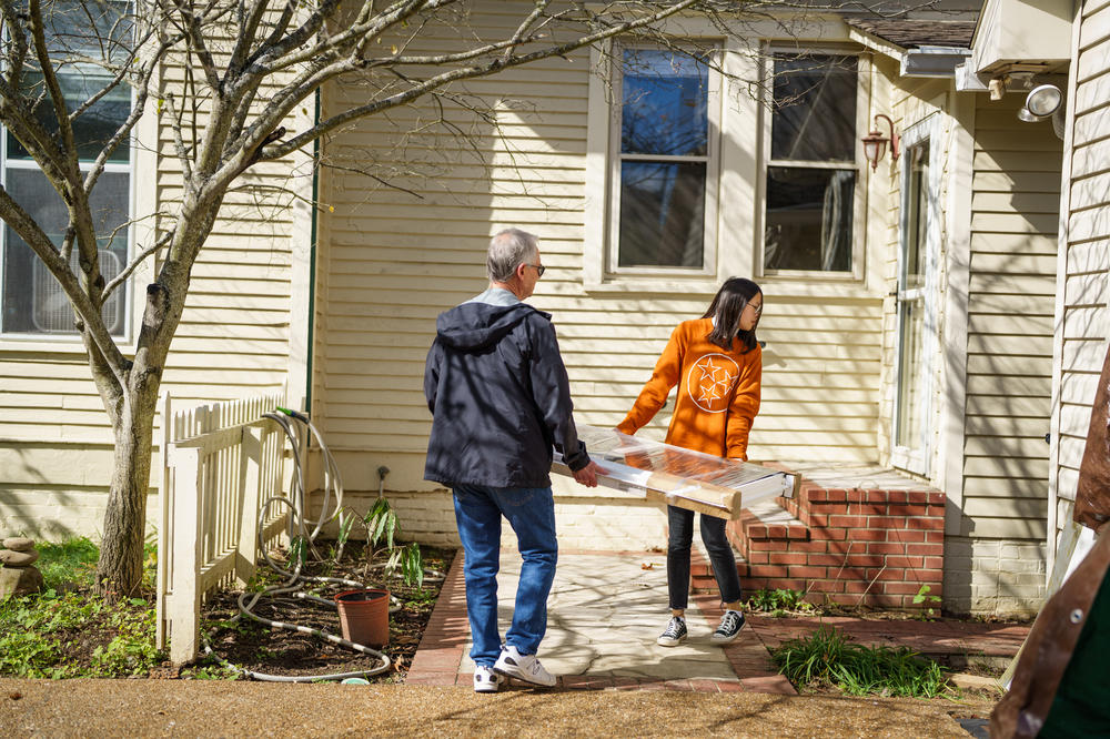 Danny Turner and his daughter, Zoe, carry a new window into their home, where they are storing materials to rebuild the property.