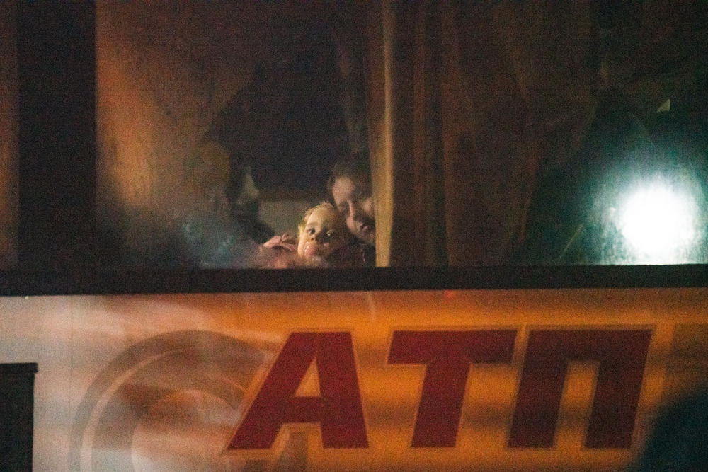 A bus brings refugees to a warehouse that's been turned into a shelter.