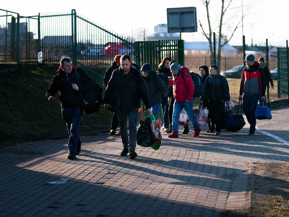 People carry suitcases towards the Medyka border crossing to enter Ukraine from Poland. People are returning to get to their families in Ukraine and also to join the Ukrainian military.
