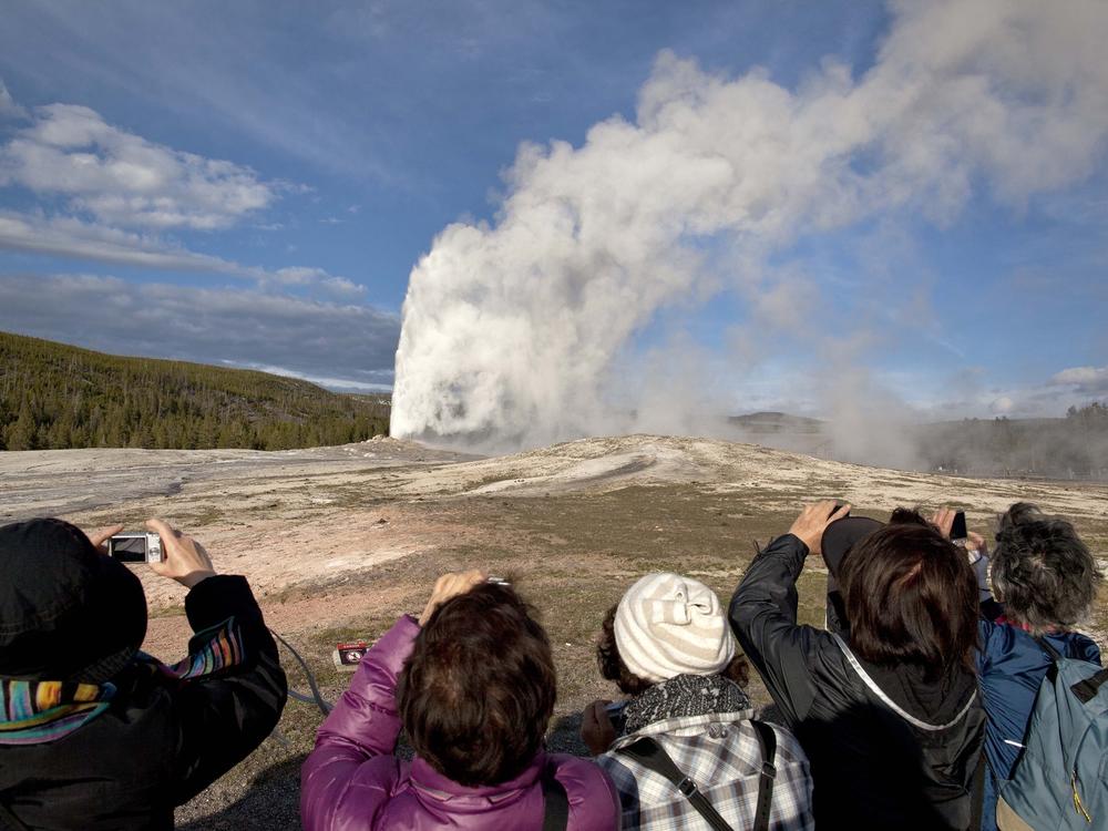Tourists photograph Old Faithful geyser erupting in 2011 in Yellowstone National Park, Wyo.
