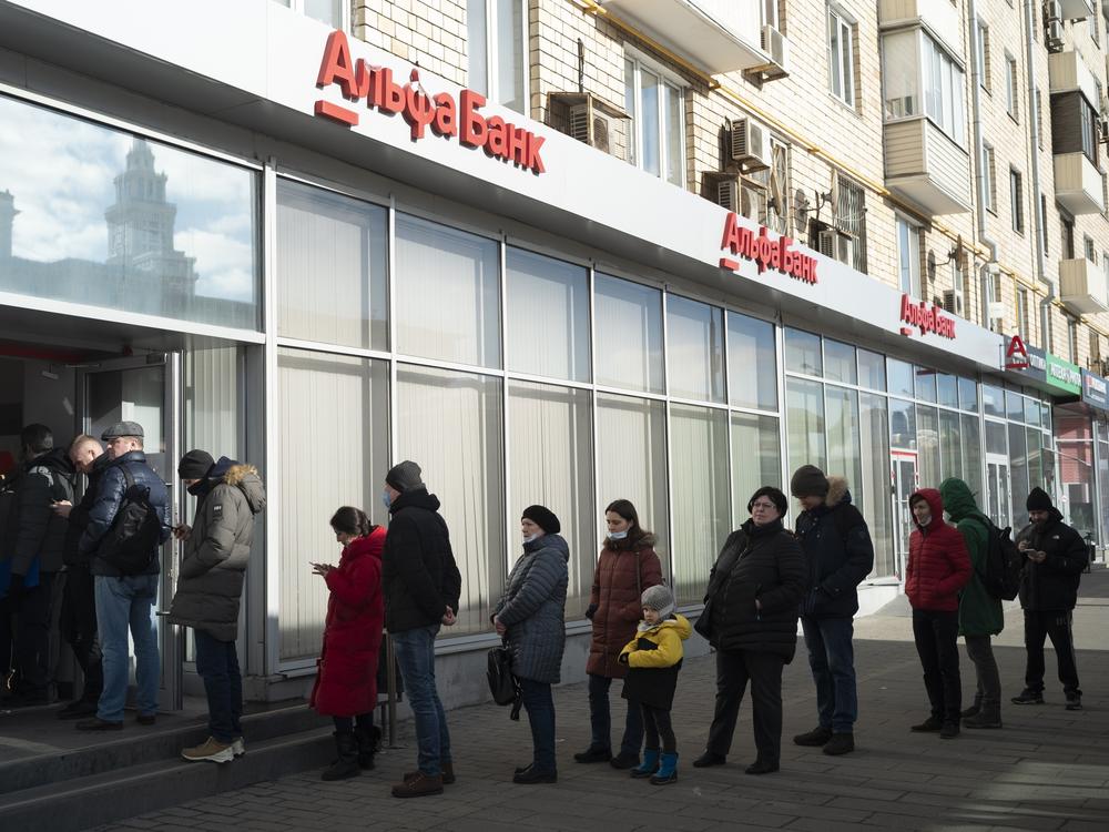 People stand in line to withdraw money from an ATM of Alfa Bank in Moscow on Sunday. Russians flocked to banks and ATMs shortly after Russia launched an attack on Ukraine and the West announced severe sanctions.