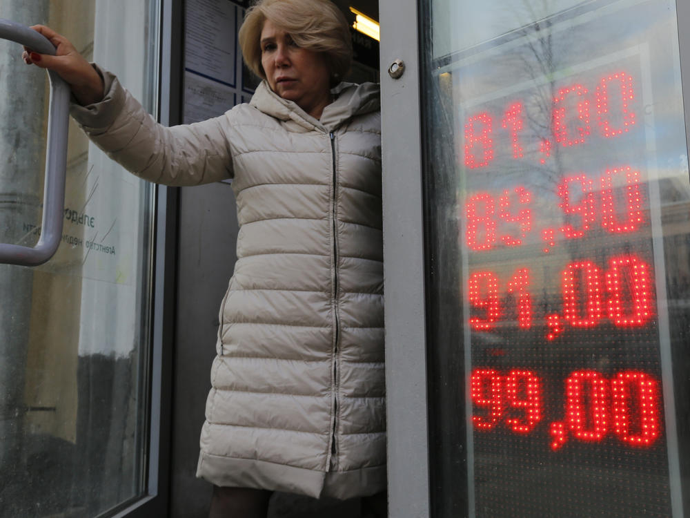 A woman leaves a Moscow exchange office with a screen showing the currency exchange rates of the U.S. dollar and the euro to Russian rubles on Feb. 24.