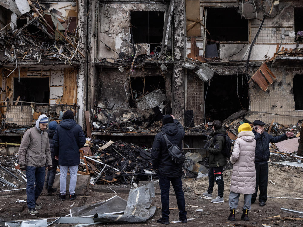 People look at the exterior of a damaged residential block hit by an early morning missile strike on Friday in Kyiv, Ukraine.