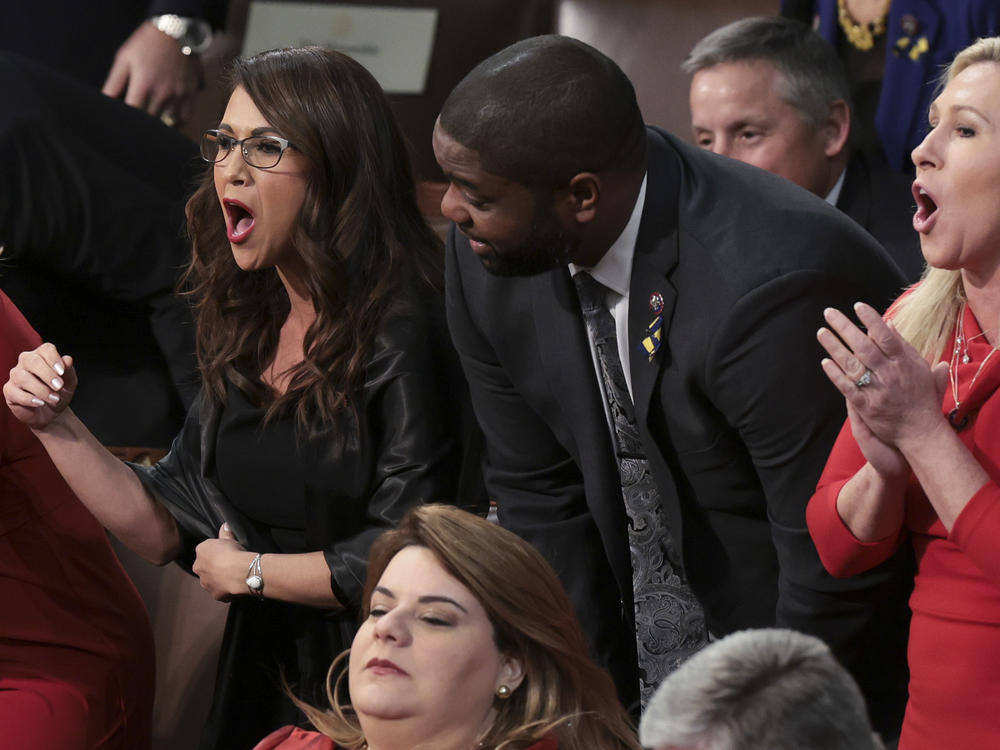 Rep. Lauren Boebert, R-Colo. (left), and Rep. Marjorie Taylor Greene, R-Ga., stand with fellow lawmakers as they listen to President Biden's State of the Union address.