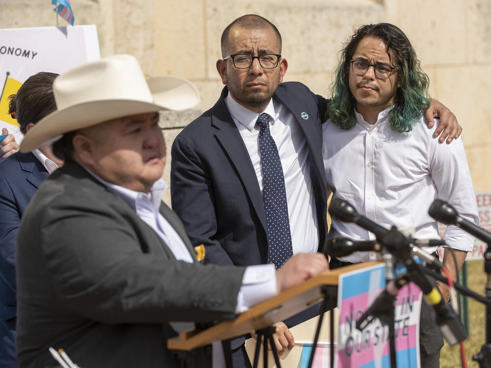 Ricardo Martinez, CEO of Equality Texas, center, and Adri Perez, ACLU of Texas policy and advocacy strategist, listen to Emmett Schelling, executive director for the Transgender Education Network of Texas, speak at a rally in support of transgender children and their families outside a hearing at the Heman Marion Sweatt Travis County Courthouse in Austin, Texas, on Wednesday.