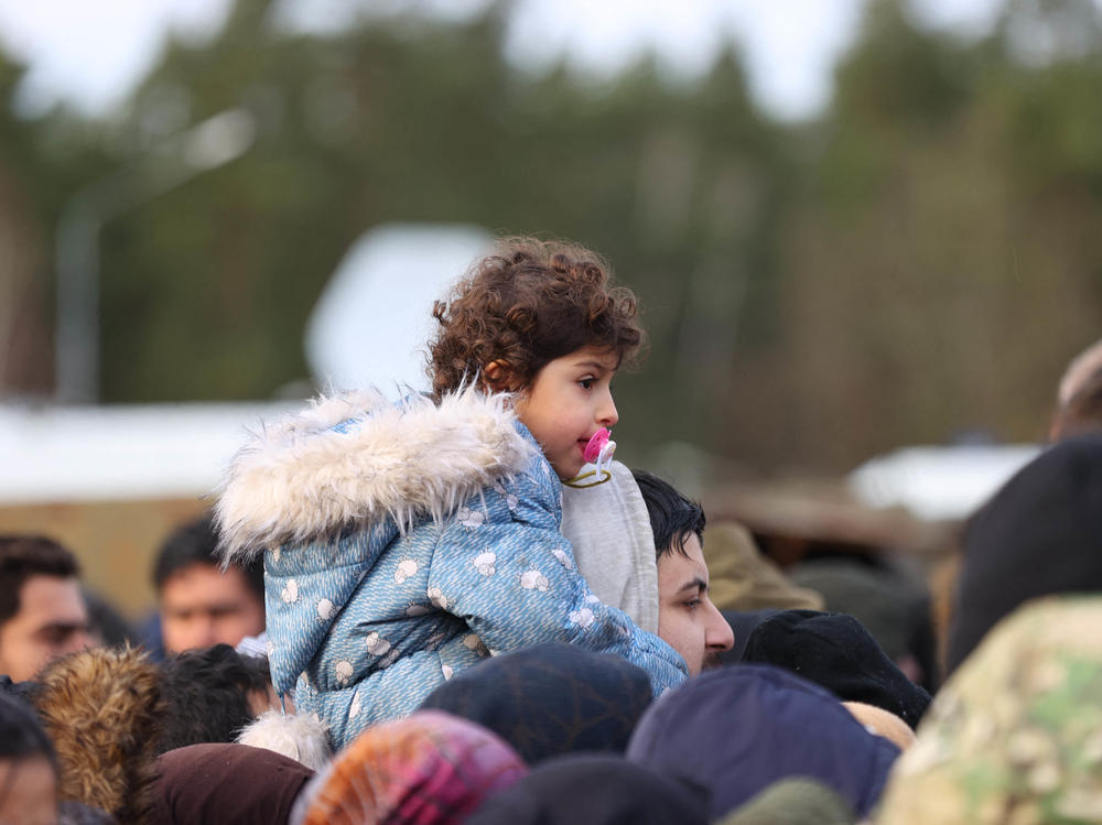 Migrants receive food outside the transport and logistics center near the Bruzgi border point on the Belarusian-Polish border in November 2021.