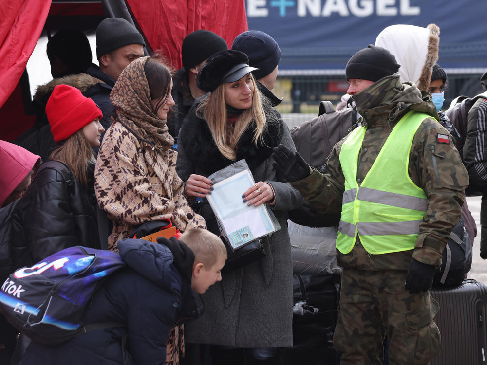 A Polish border guard speaks with women and children fleeing Ukraine at a border crossing on Wednesday near Korczowa, Poland.