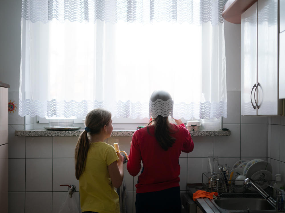Two Ukrainian girls in foster care look out the window of a home they are now sharing with a Polish foster family in Bilgoraj, Poland. More than 1.5 million Ukrainians — many of them children — have fled since the Russian invasion.