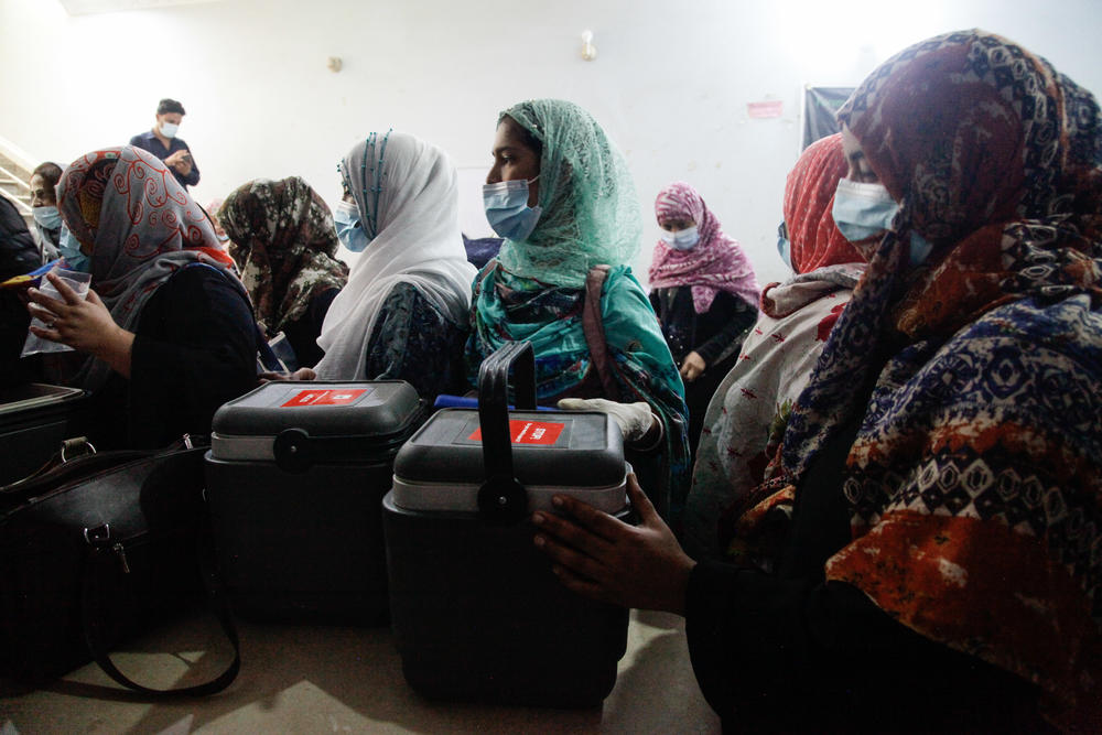 Female health workers wait for medics to fill their cooler boxes with a variety of vaccines – from Pfizer to China's Sinovc to Russia's Sputnik V. Health officials say offering residents a variety of vaccine brands helps them overcome hesitation.