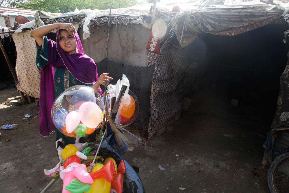 A young woman in the informal Hindubasti settlement in Karachi, holds the balloons that her father sells to provide a livelihood for them all. It's scarcely enough, says the woman's mother, Kamli. 