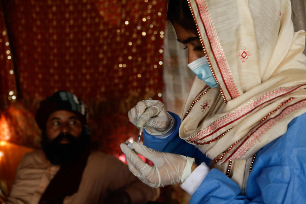 Namra, a 21-year-old health worker, prepares a syringe with COVID-19 vaccine at the house of Kamran, in the informal Hindubasti settlement in Karachi.
