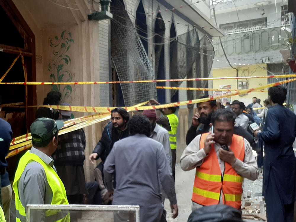 Rescue workers and volunteers gather at the site of bomb explosion in Peshawar, Pakistan, on Friday.