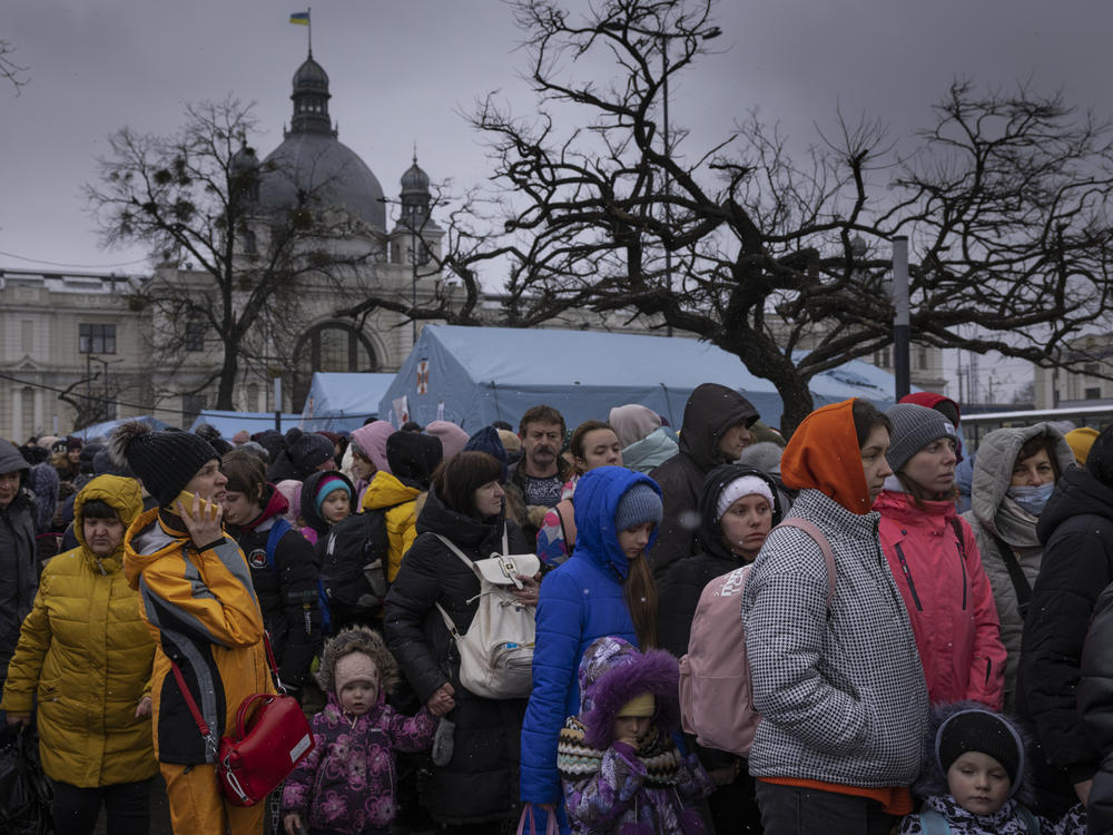 Families wait to make their way from the main bus and train terminal on Saturday in Lviv, Ukraine. More than 1 million people have fled Ukraine following Russia's assault on the country, with many Ukrainians passing through Lviv on their way to Poland.