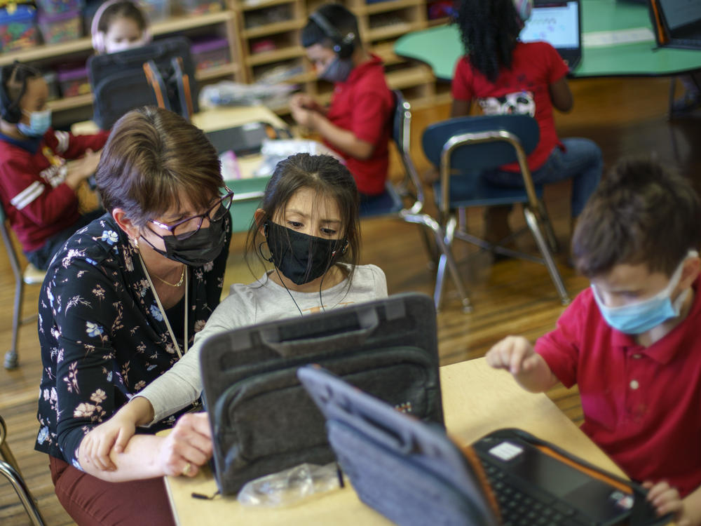 Kindergarten teacher Karen Drolet works with a masked student at Raices Dual Language Academy, a public school in Central Falls, R.I., on Feb. 9, 2022.