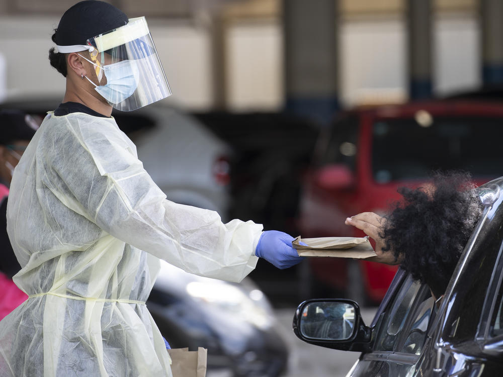 A health worker gives out rapid COVID-19 antigen self-test kits at the Waipareira Trust drive-in COVID-19 testing station in Auckland, New Zealand, on Tuesday.