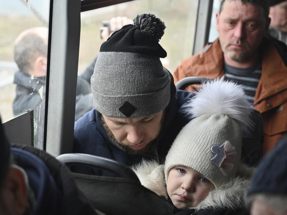 Refugees fleeing the military operation zone from the Mariupol area of Ukraine sit in a bus as they arrive at the border crossing in Veselo-Voznesenka, Russia, on Monday.