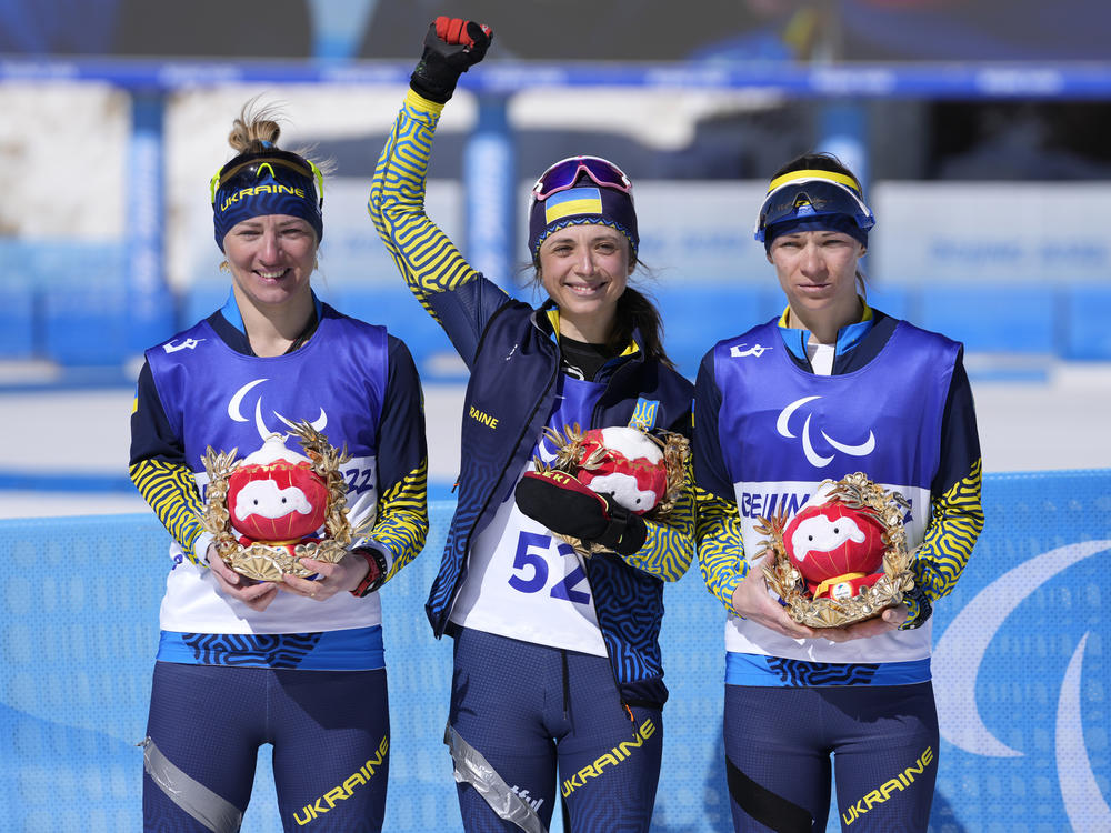 Gold medalist Iryna Bui (center) silver medalist Oleksandra Kononova (left) and bronze medalist Liudmyla Liashenko celebrate after the women's biathlon middle distance standing event at the 2022 Winter Paralympics on Tuesday.