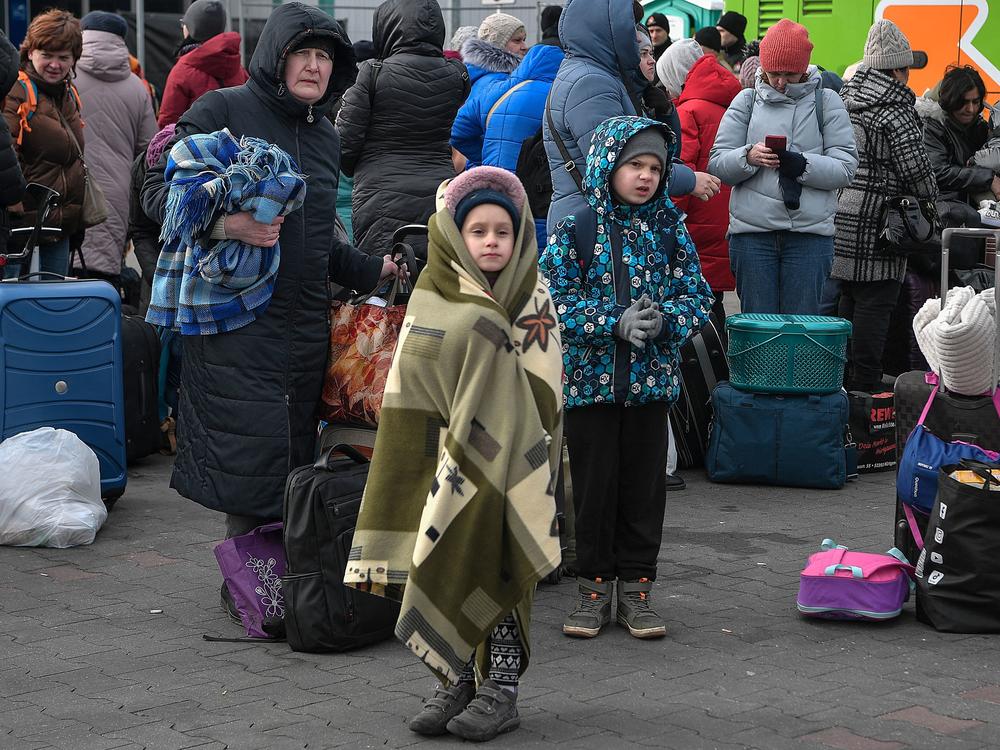 People wait to board buses taking them further into Poland or abroad from a temporary refugee shelter in a former shopping center near the Polish city of Przemysl on Tuesday.