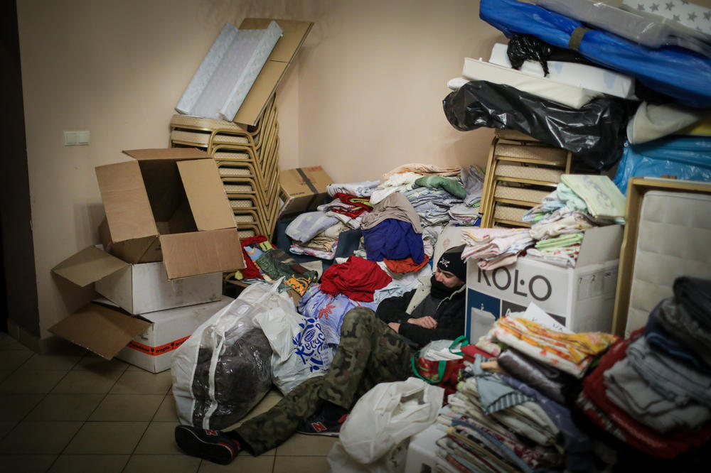 Piotr Mastalerz, exhausted from days of working around the clock as a volunteer, sleeps among piles of donated clothes and fabric.