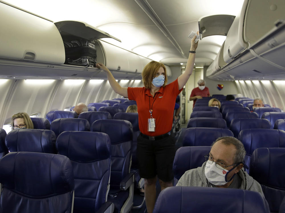 In this 2020 photo, a Southwest Airlines flight attendant prepares a plane for takeoff at the Kansas City International airport in Kansas City, Mo. TSA's travel mask mandate has been extended a month, to April 18, 2022.