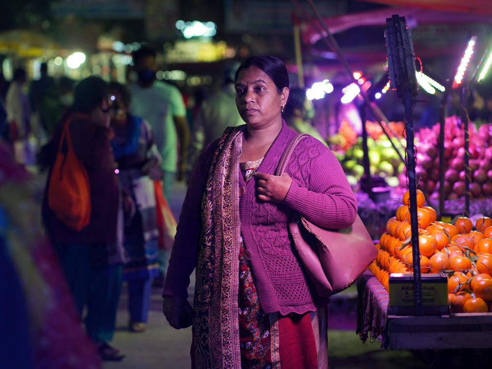 <em>Radha Devi buys vegetables on her way back from the private educational institute where she has worked as an aide since November 2021. Devi, her husband and their three children all came down with COVID-19 in April of that year. She and the kids recovered; her husband died. Says Devi: 