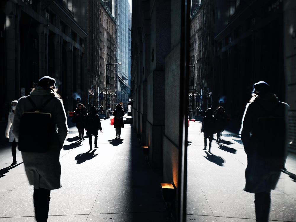 People walk along Wall Street near the New York Stock Exchange, in New York City. The stock market has been volatile as the war in Ukraine and high oil prices continues to worry investors. Americans' stress about global uncertainty is high, according to a new survey.