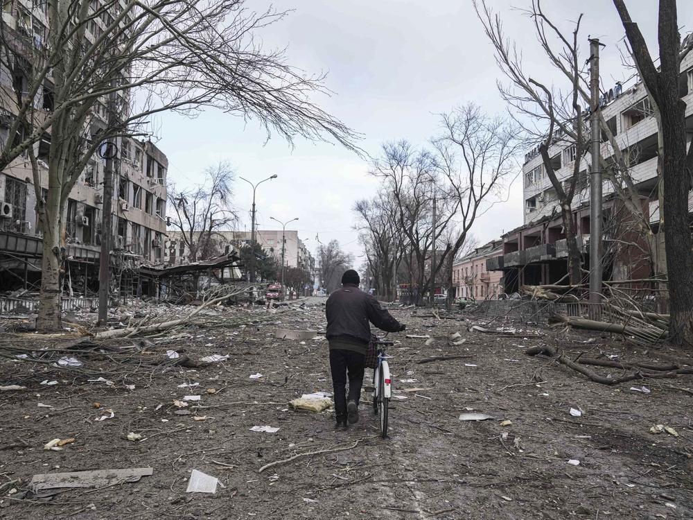 A man walks with a bicycle in a street damaged by shelling in Mariupol on Thursday.