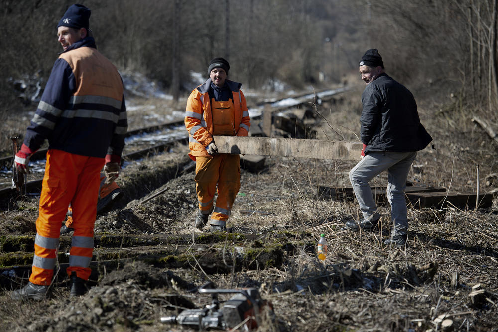 It takes two men to carry the heavy wooden rail ties that are screwed to the tracks.