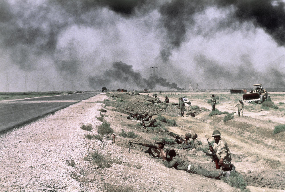 Iraqi troops are beside a roadway in Iran on Oct. 17, 1980. The smoke in the background is from fires along pipelines used to carry oil from the giant refinery at Abadan to Ahwaz and Tehran.