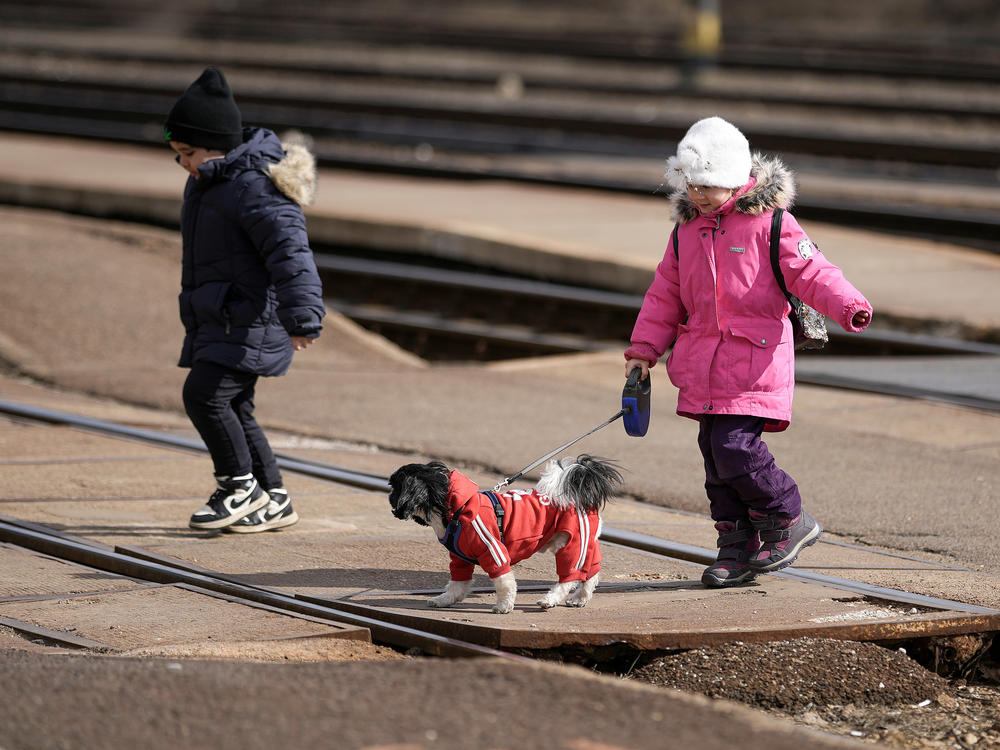 Two young refugees fleeing Ukraine arrive at the border train station of Zahony with a dog on March 10 in Zahony, Hungary. Hungary, one of Ukraine's neighboring countries, has welcomed more than 144,000 refugees fleeing Ukraine after Russia began a large-scale attack on Ukraine on Feb. 24.
