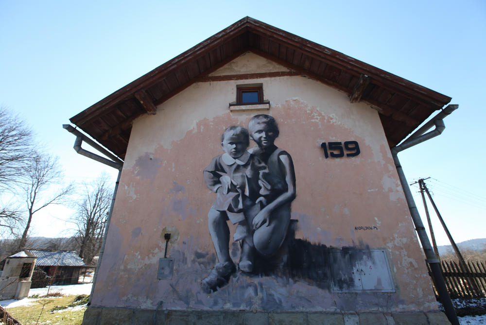 A mural is seen here on the side of a building near the construction on the rails.
