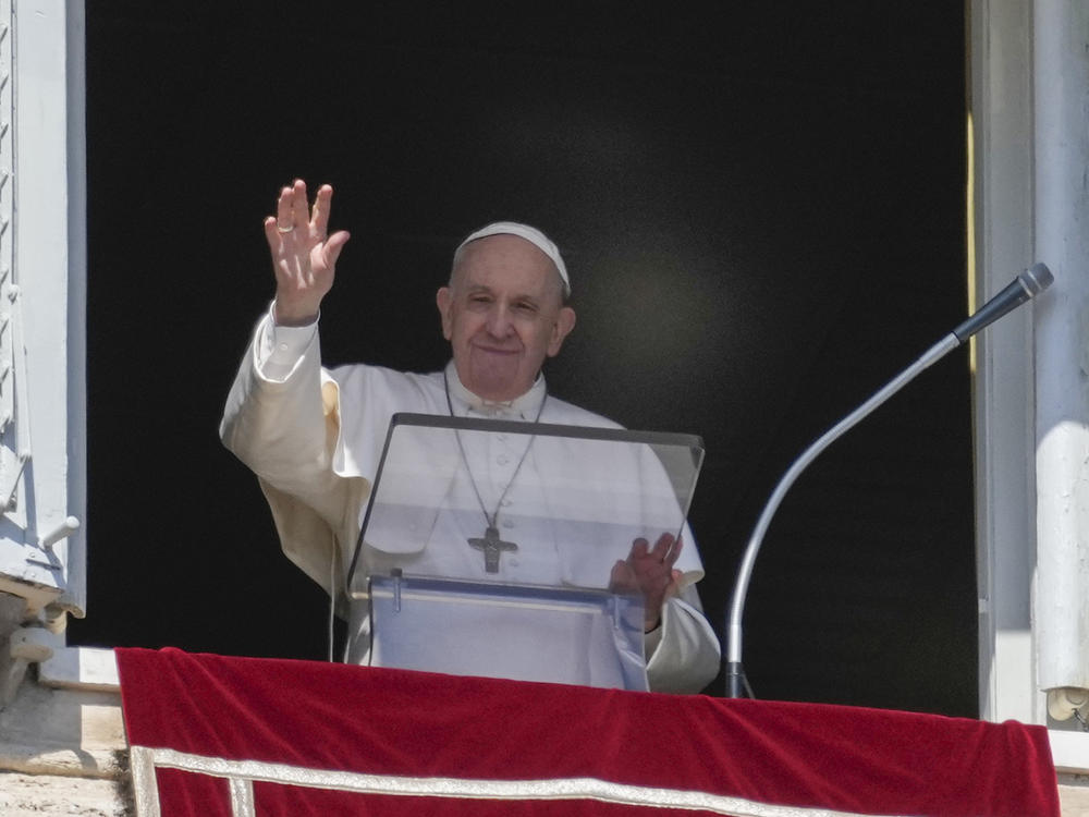 Pope Francis waves during the Angelus noon prayer from the window of his studio overlooking St. Peter's Square at the Vatican on Sunday.