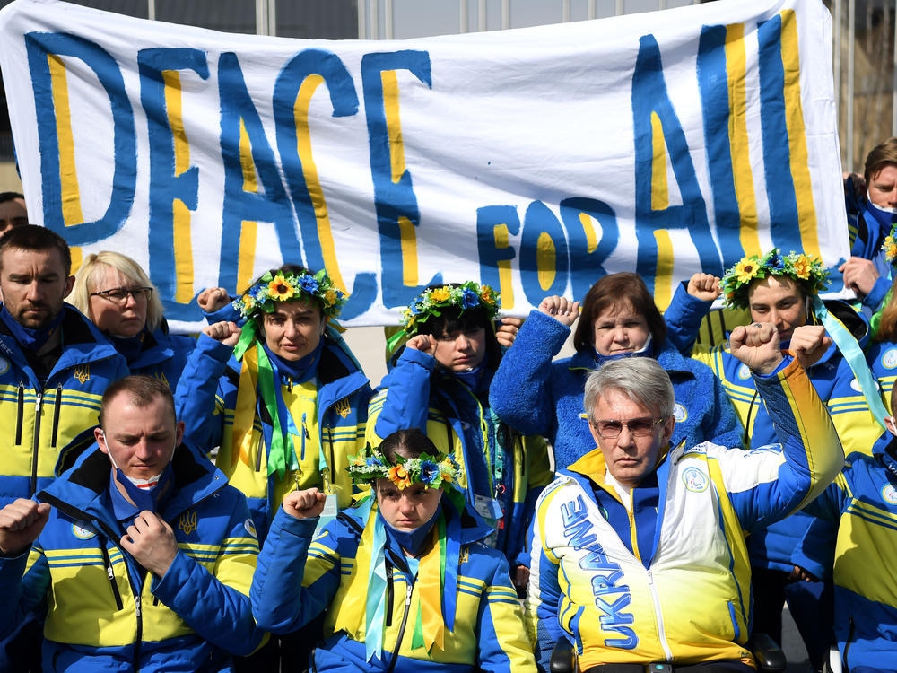 President of Ukraine's Paralympic Committee Valerii Sushkevych and members of Team Ukraine hold a banner up reading 