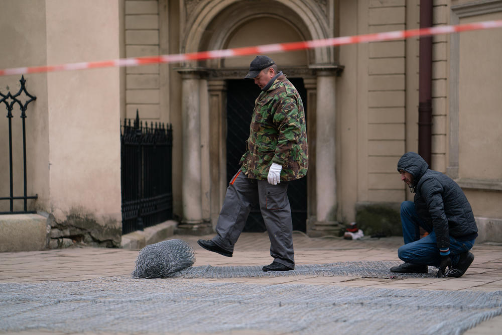 Men work to cover the windows of the outside the city's Armenian Cathedral with protective wire.