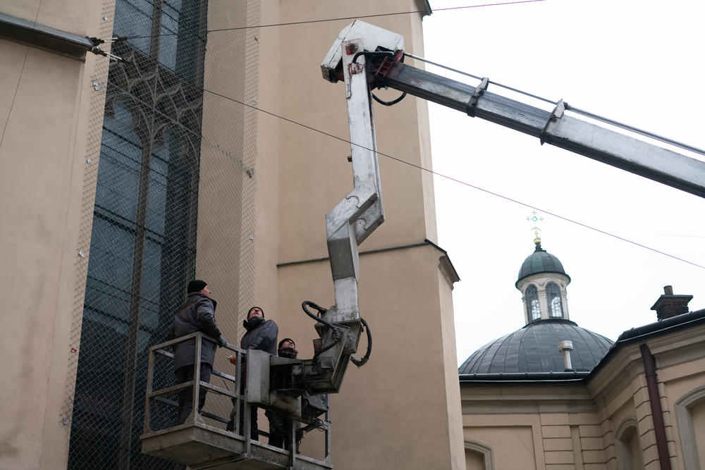 A crane lifts workers up so they can protect the stained glass windows at Lviv's Roman Catholic cathedral.