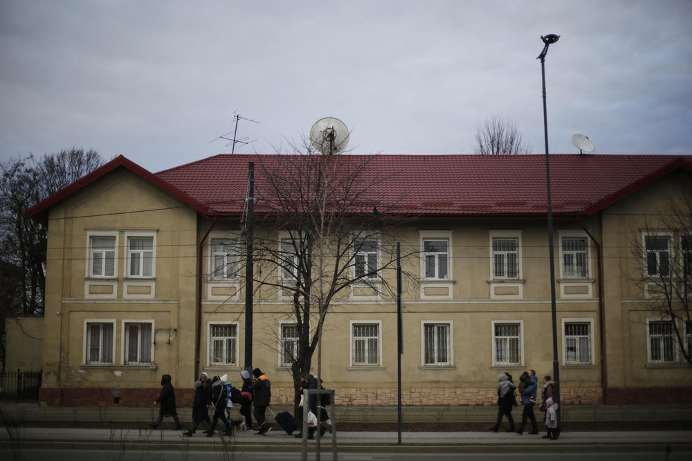 Ukrainians uprooted by war walk toward the train station in central Lviv.