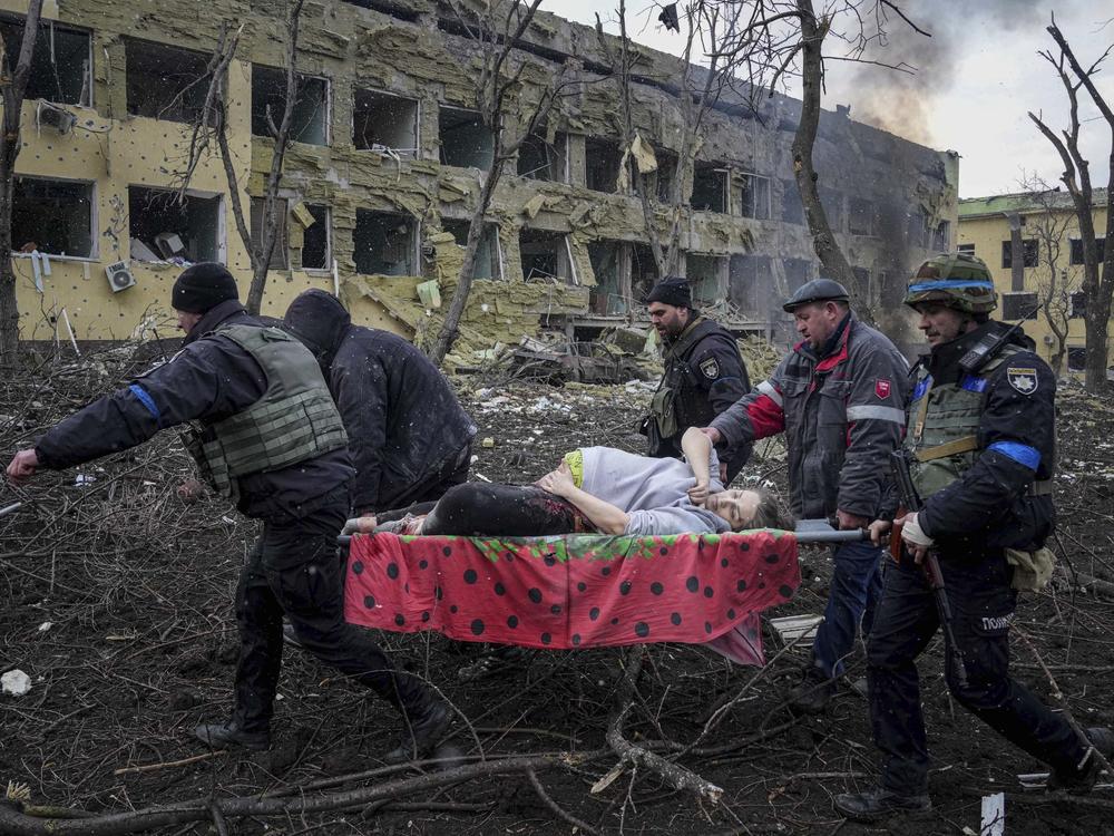 First responders and volunteers carry an injured pregnant woman from a maternity hospital that was damaged by shelling in Mariupol, Ukraine, on Wednesday. The woman and her baby have since died.