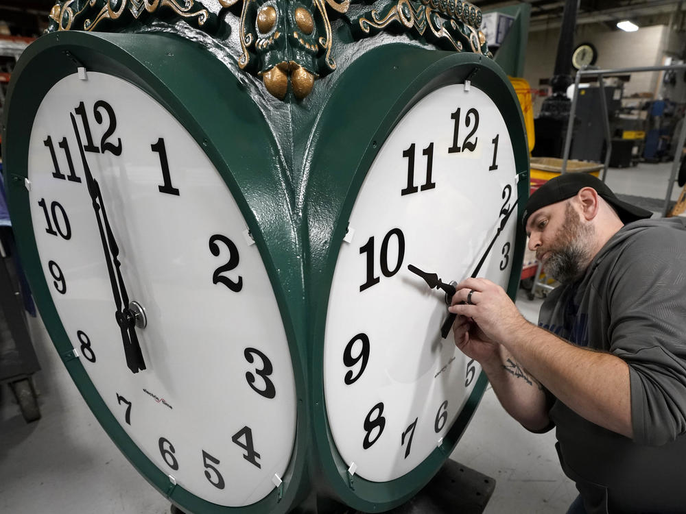 A clock technician adjusts the hands on a large outdoor clock under construction at Electric Time Company in Medfield, Mass, last year, just days before daylight saving time was set to end.