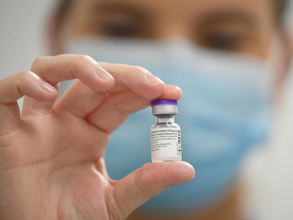 A staff member poses with a vial of Pfizer-BioNTech COVID-19 vaccine at a vaccination health center.