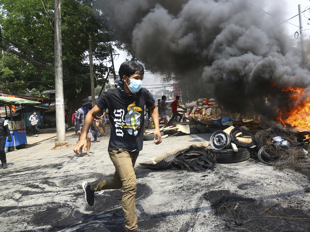 Anti-coup protesters are shown running around their makeshift barricade as they make a defense line during a demonstration in Yangon, Myanmar, on March 28, 2021.