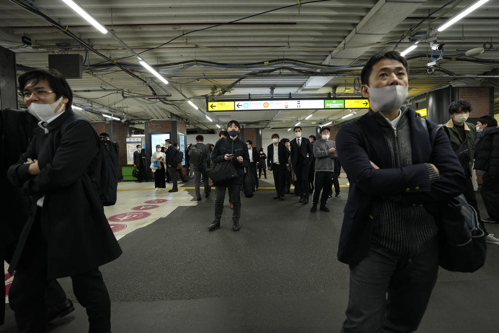People wait at a train station in Tokyo on Wednesday, as all services were suspended after the 7.3 magnitude earthquake hit.