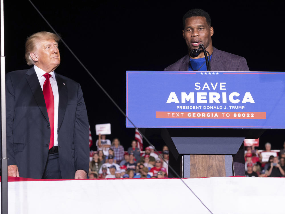 Former President Donald Trump listens as Georgia Senate candidate Herschel Walker speaks during his Save America rally in Perry, Ga., on Sept. 25, 2021.