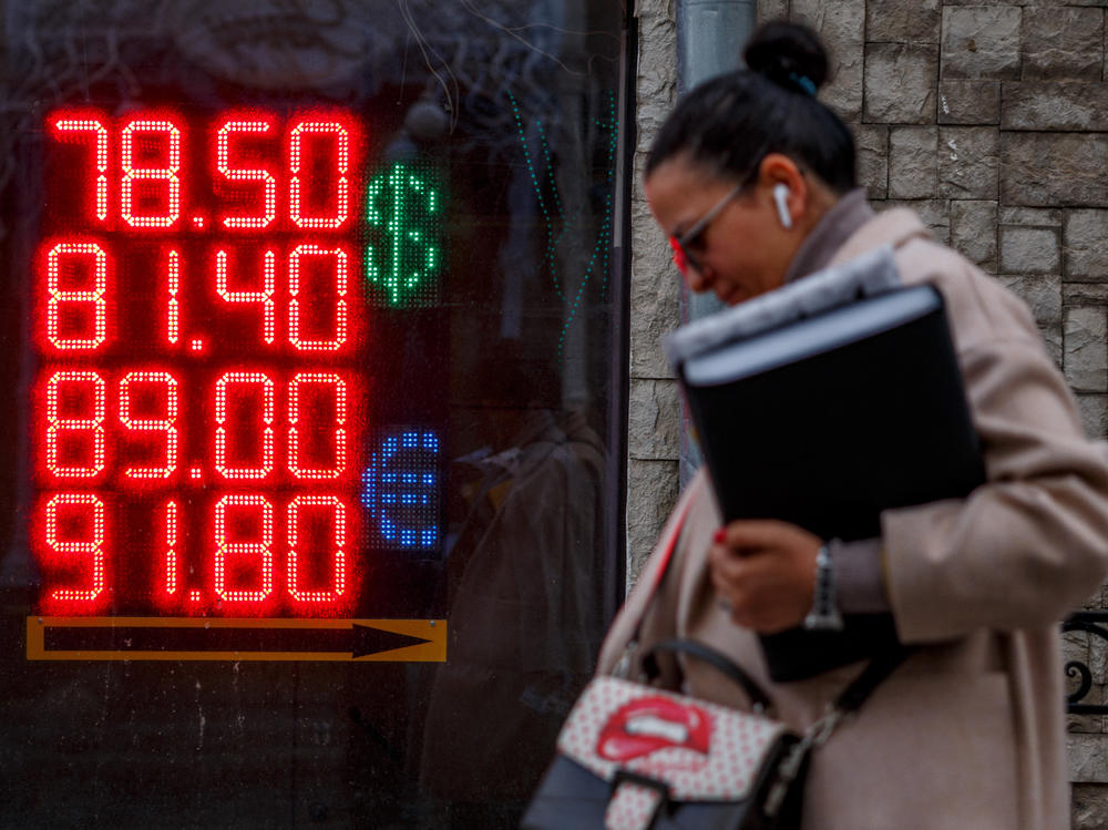 A woman walks past a display showing currency exchange rates of the U.S. dollar and the euro against the Russian ruble in Moscow on Feb. 22. Russia owes over $100 million in interest payments for two bonds on Wednesday as fears grow that the country will default on its debt.