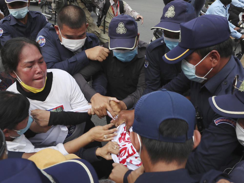 Local security personnel try to grab a banner from supporters of the Cambodia National Rescue Party in front of the Phnom Penh Municipal Court Thursday in Phnom Penh, Cambodia.