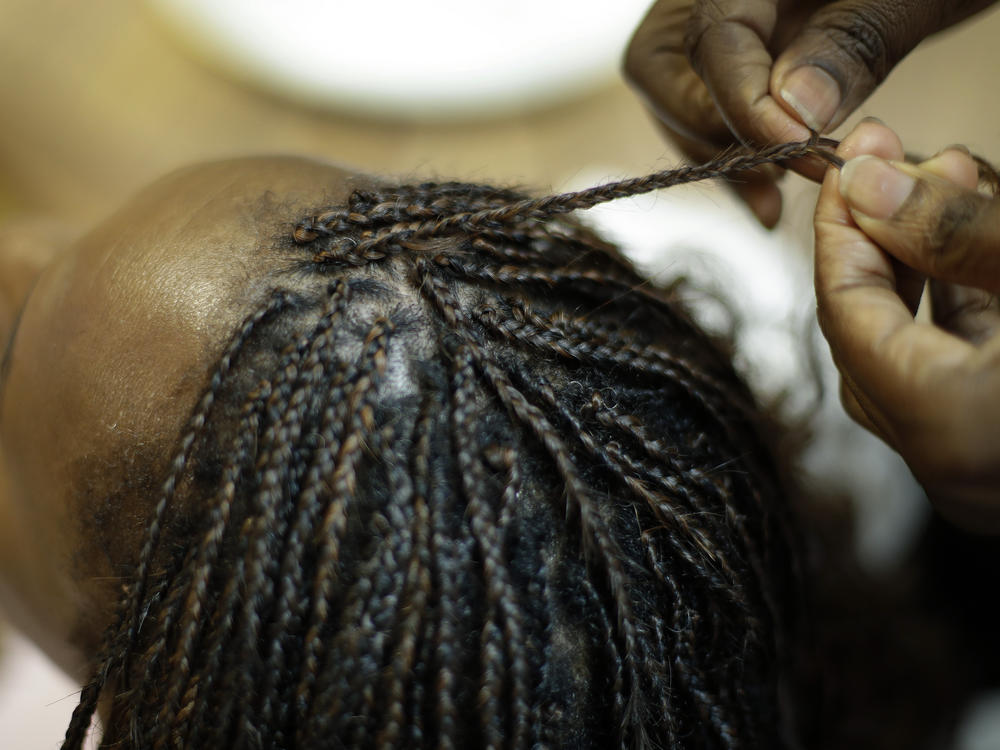 Shelly Smith braids hair at her salon, Braid Heaven, in this Jan. 28, 2020 file photo. The House on Friday, March 18 voted to prohibit discrimination on the basis of hair texture and hairstyles like hair that is tightly coiled, curled, or worn in locs and other styles.